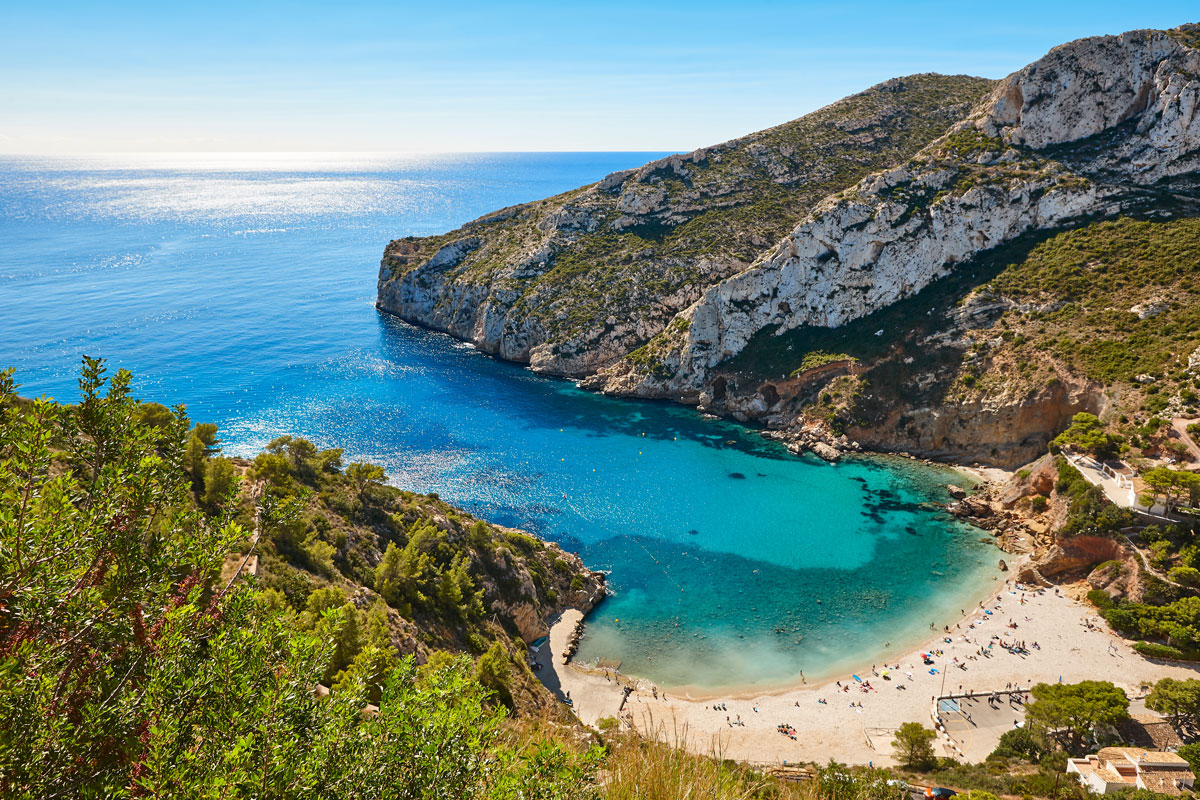 Turquoise water at Cala Granadella with limestone cliffs