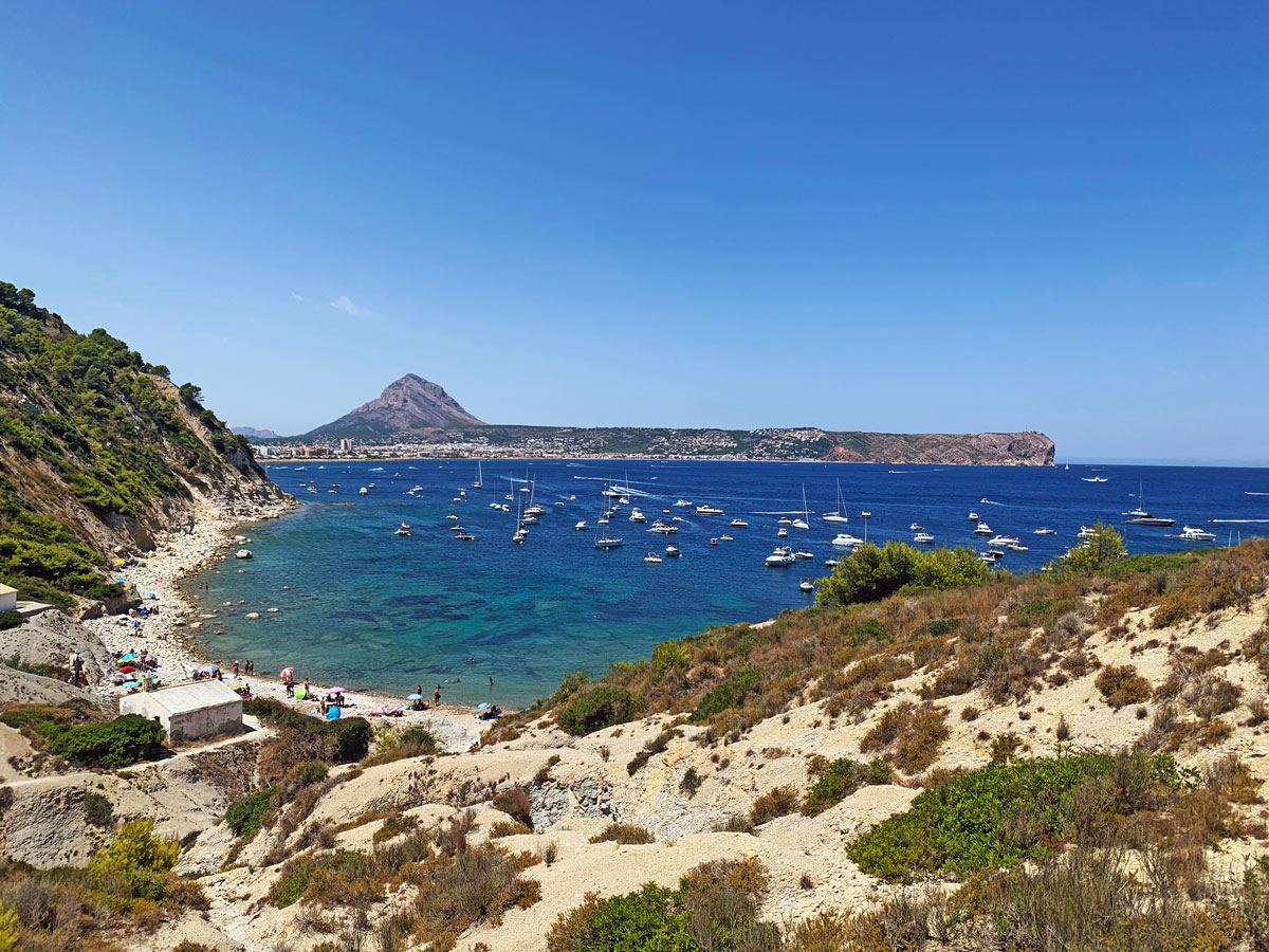 Clear water at Cala Sardinera with rocky coastline and Mediterranean vegetation